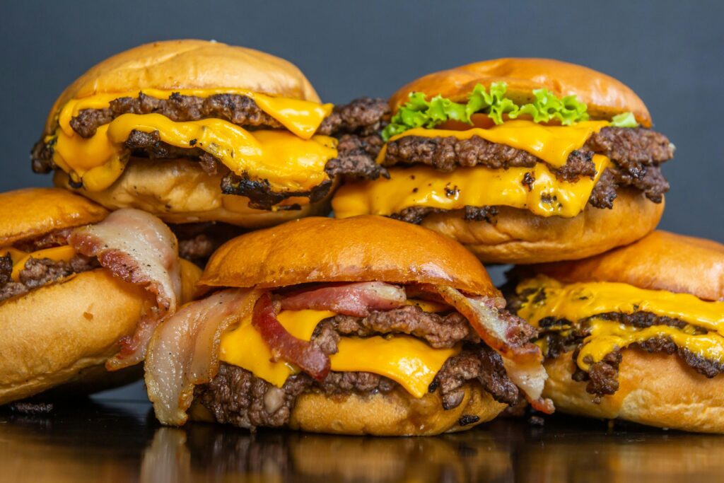 Close-up of double cheeseburgers with bacon, lettuce, and tomato, showcasing juicy beef and melted cheese for a tasty meal.
