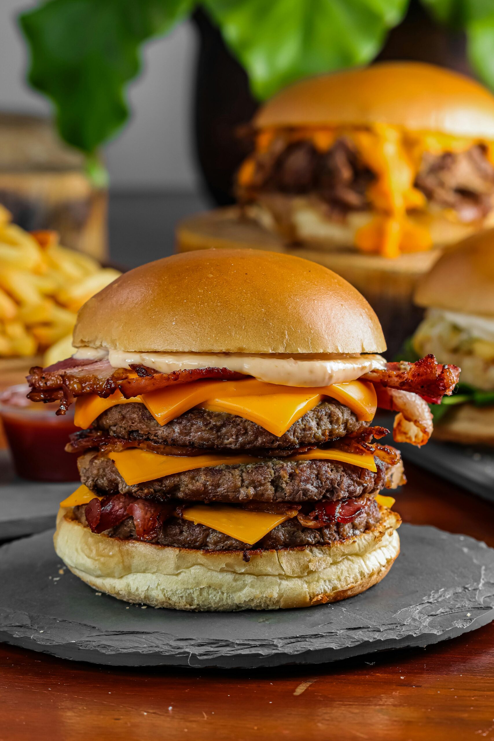 Delicious triple bacon cheeseburger stacked with cheese and garnished with fries.