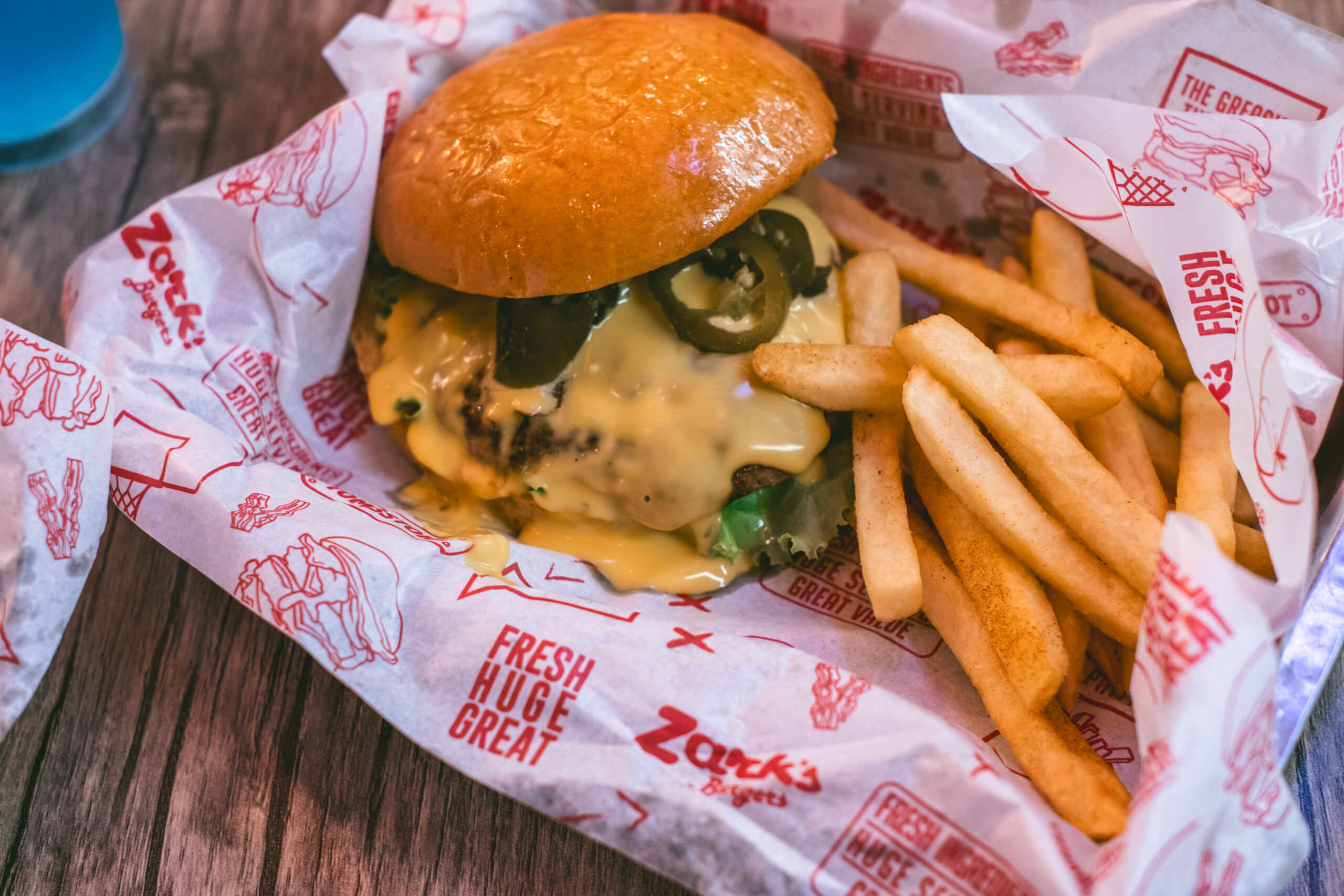 Mouth-watering cheeseburger with jalapenos and crispy fries in fast food restaurant.